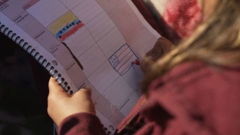 Rubi, Francisco's daughter, draws a US flag right next to a Venezuelan flag, her country of birth at an encampment for migrants.