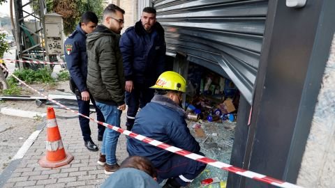 A Palestinian man watches as police officers inspect a damaged store in the aftermath of an Israeli army raid in Nablus.