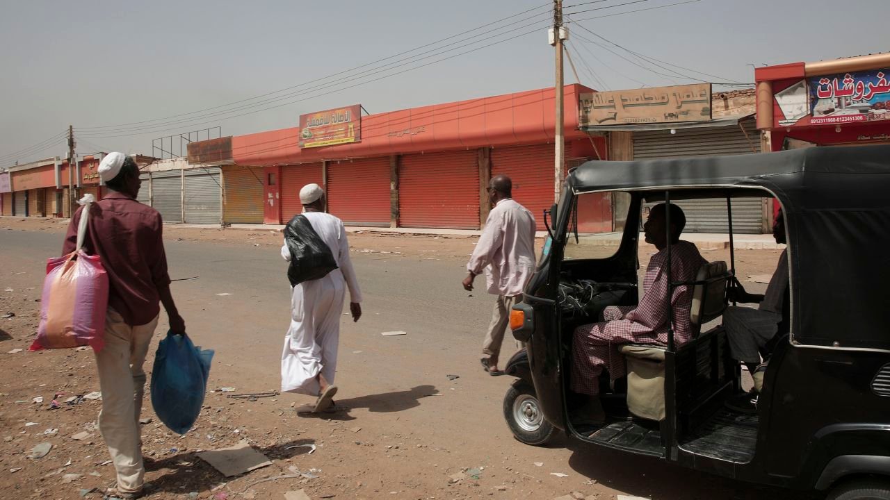 People walk past shuttered shops in Khartoum, Sudan, Monday, April 17, 2023.