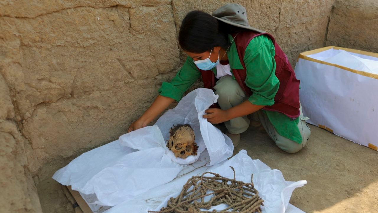 A worker wraps skeletal remains and parts of the mummy's funerary bundle.