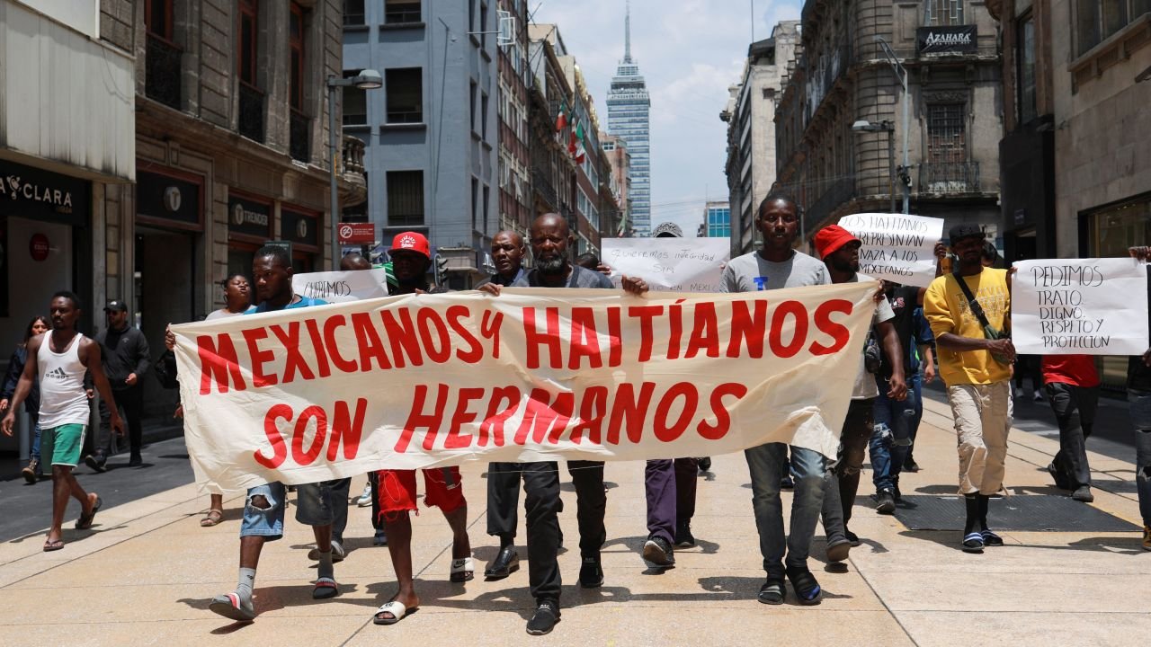 Migrants, mostly from Haiti, take part in a protest with a banner that reads 